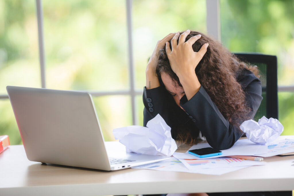 An unhappy female with an entry-level job touching her head while working.