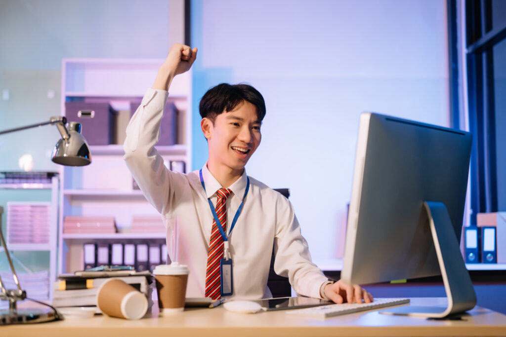 A male employee received a job promotion, celebrating in the office with a raised hand.
