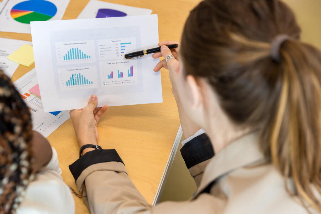 A female employee pointing the results of their market research with a pen.